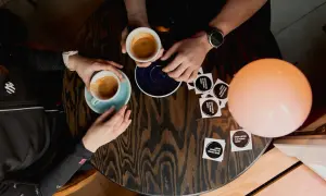 Dwie osoby przy stoliku piją kawę. Rozmowa o autofagii i dobrej kawie przy filiżankach espresso.