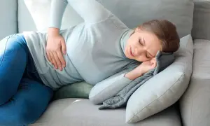 Kobieta z bólem brzucha szuka ulgi, wypróbowując na ból brzucha domowe sposoby.