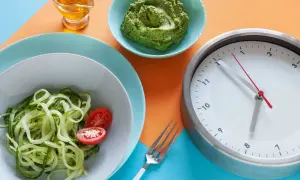 Zegar pokazuje 12:55. Czy kawa kuloodporna przerywa post? Obok talerz z cukinią i pomidorkami, miseczka z zielonym pesto i oliwa.