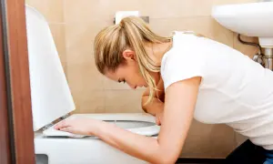Kobieta pochyla się nad toaletą, szukając domowych sposobów na wymioty.