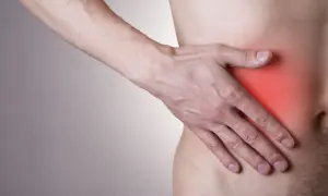 Mężczyzna trzyma rękę na boku, gdzie czerwony obszar sugeruje, że boli wątroba.