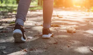 Nogi w butach sportowych idące ścieżką. Czy chodzenie odchudza? Regularny ruch to klucz do zdrowia i dobrej sylwetki.