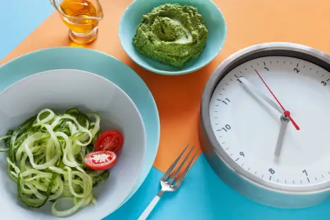 Zegar pokazuje 12:55. Czy kawa kuloodporna przerywa post? Obok talerz z cukinią i pomidorkami, miseczka z zielonym pesto i oliwa.