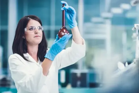Naukowczyni w laboratorium bada płyn w kolbie. Czy leczenie biologiczne to chemia? Badania naukowe pomagają odpowiedzieć na to pytanie.