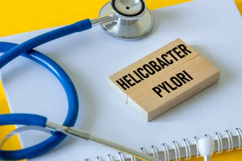 Stetoskop i klocki z napisem "Helicobacter pylori" symbolizują problemy zdrowotne, w tym potencjalne helicobacter pylori objawy psychiczne.