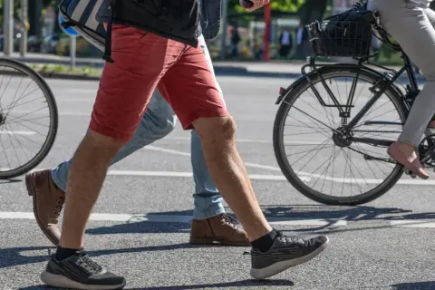 Ludzie idący i jadący na rowerze. Jazda na rowerze angażuje mięśnie brzucha, pomagając w utrzymaniu równowagi.